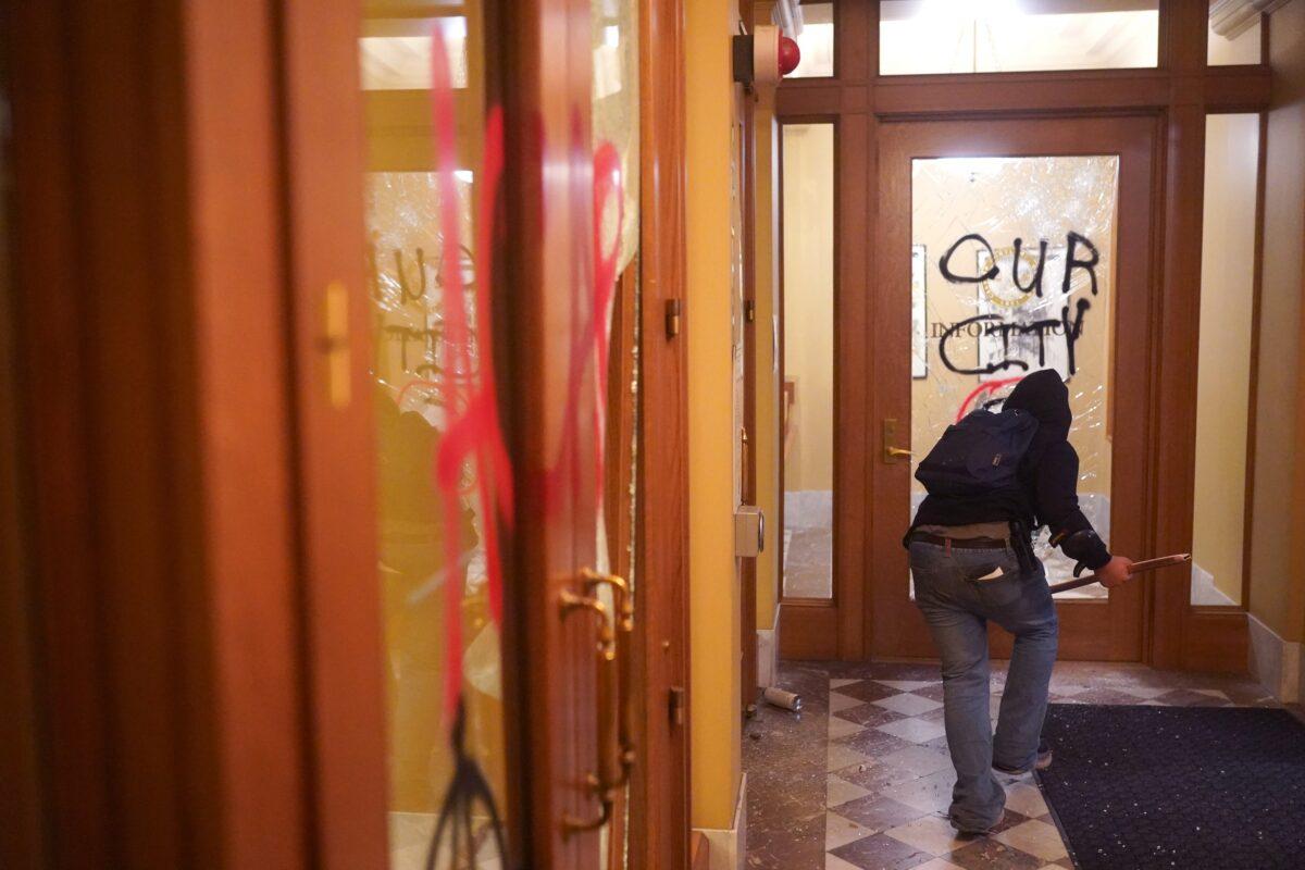A rioter runs through the vandalized lobby of City Hall in Portland, Ore., late Aug. 25, 2020. (Nathan Howard/Getty Images)