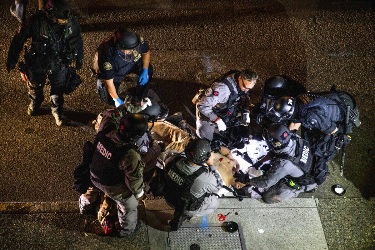 A man is treated after being shot in Portland, Ore., Aug. 29, 2020. The victim was later identified as Aaron Jay Danielson, who died from his wounds. Michael Reinoehl, an Antifa member, admitted to shooting Danielson. (Paula Bronstein/AP Photo)