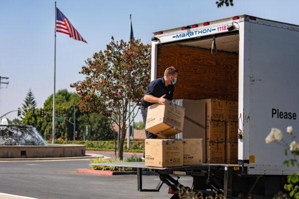 A man piles boxes of donated masks into a truck in the parking lot of the Richard Nixon Library in Yorba Linda, Calif., on Sept. 1, 2020. (John Fredricks/The Epoch Times)