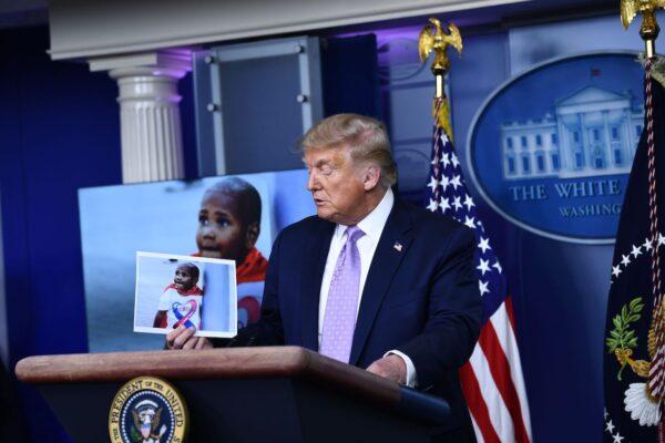 President Donald Trump holds up a photo of LeGend Taliferro, a victim of a crime, during a news conference in the White House in Washington, on Aug. 13, 2020. (Brendan Smialowski/AFP via Getty Images)