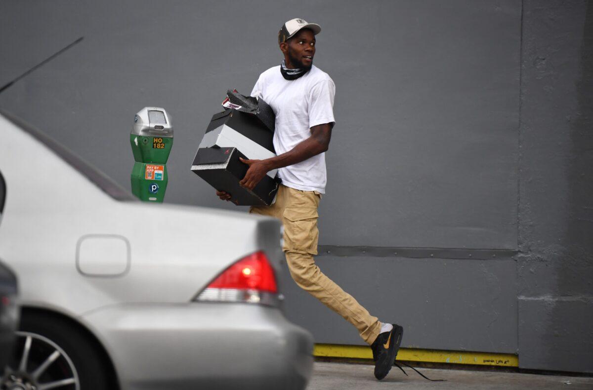 A man runs with boxes of shoes after looters broke into a shoe store, in Hollywood, Calif., on June 1, 2020. (Robyn Beck/AFP via Getty Images)