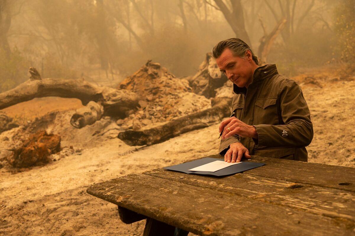 California Gov. Gavin Newsom signs Assembly Bill 2147 after he toured the North Complex Fire zone with California Secretary for Environmental Protection Jared Blumenfeld and California Secretary for Natural Resources Wade Crowfoot in Butte County outside of Oroville, Calif., on Sept. 11, 2020. (Paul Kitagaki Jr./Pool/The Sacramento Bee via AP)