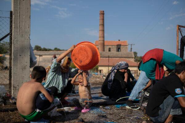 A woman washes a girl as migrants gather near Mytilene town, on the northeastern island of Lesbos, Greece, on Sept. 12, 2020. (Petros Giannakouris/AP Photo)
