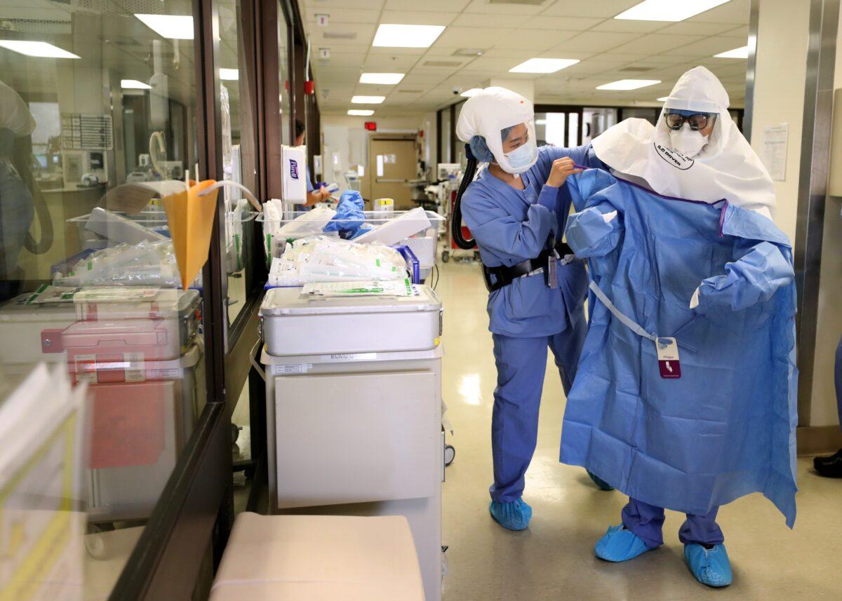 A nurse helps a doctor put on his personal protective equipment (PPE) before performing a procedure on a patient with COVID-19 in the intensive care unit at Regional Medical Center in San Jose, Calif., on May 21, 2020. (Justin Sullivan/Getty Images)