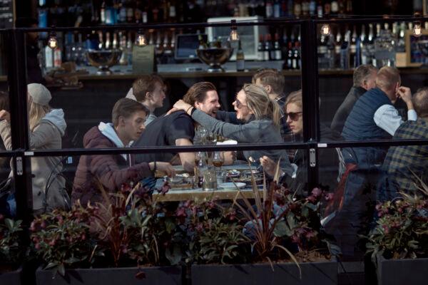 A couple hug and laugh as they have lunch in a restaurant in Stockholm. on April 4, 2020. (Andres Kudacki/AP Photo)