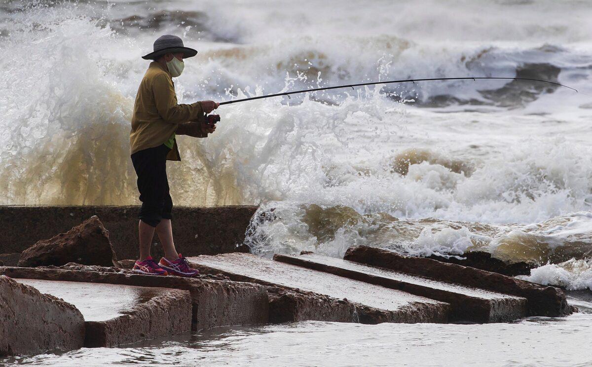Waves crash as Houston resident Tinh Pham fishes from the rocks at Diamond Beach on the west end of the Galveston Seawall in Galveston, Texas, on Sept. 19, 2020. (Stuart Villanueva/The Galveston County Daily News via AP)