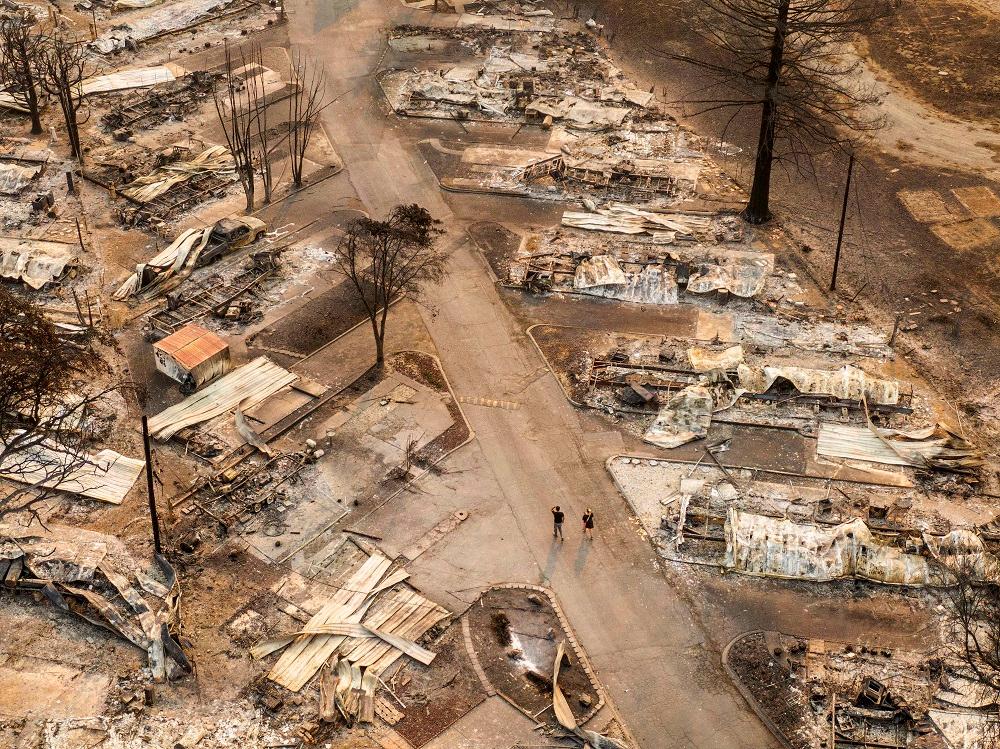 In this aerial view from a drone, people walk through a mobile-home park destroyed by fire on Sept. 10, 2020, in Phoenix, Ore. Hundreds of homes in the town have been lost due to wildfire. (David Ryder/Getty Images)