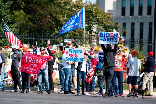 A supporter of Joe Biden and Sen. Kamala Harris (D-Calif.) holds a sign amid a crowd of President Donald Trump supporters, outside of Walter Reed Medical Center in Bethesda, Md., on Oct. 4, 2020. (Alex Edelman/AFP via Getty Images)