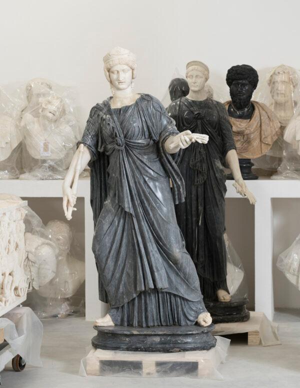 Group of restored sculptures: Two statues of Isis in gray morato marble stand in front of the busts of emperors and the bust of a drunken satyr. (Lorenzo De Masi/Torlonia Foundation)