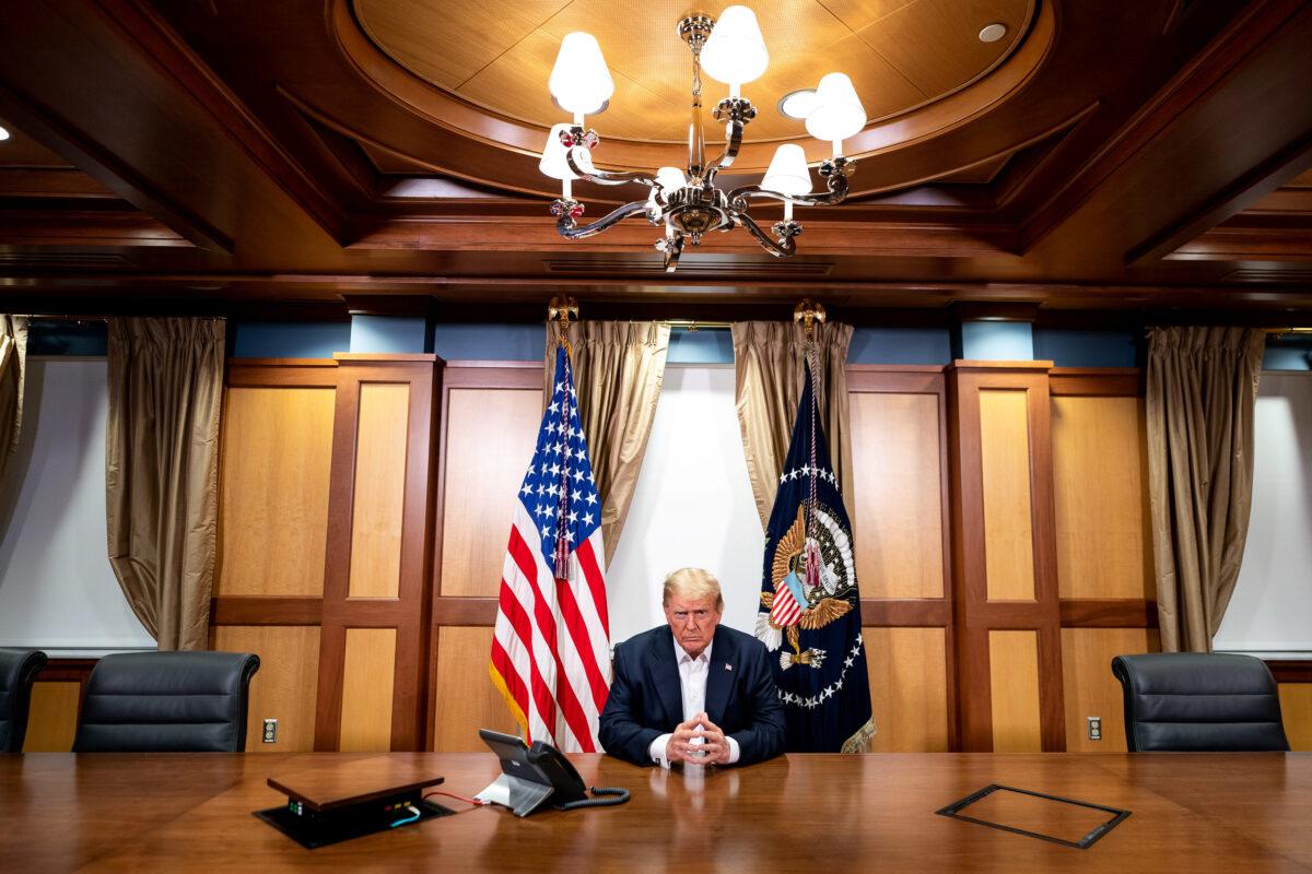 President Donald Trump participates in a phone call with Vice President Mike Pence, Secretary of State Mike Pompeo, and Chairman of the Joint Chiefs of Staff Gen. Mark Milley in his conference room at Walter Reed National Military Medical Center in Bethesda, Md., on Oct. 4, 2020. (Tia Dufour/The White House/Handout via Reuters)