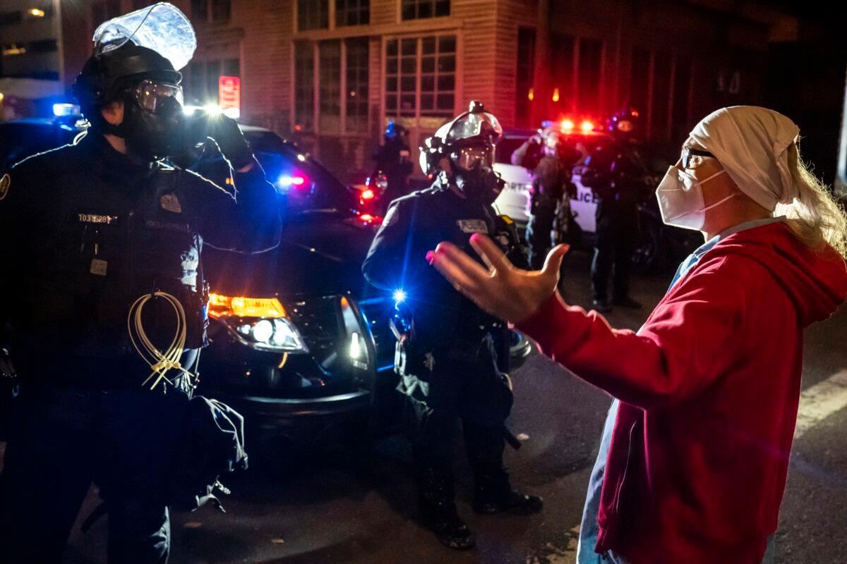 Gwen Boucher, a resident in a neighborhood that was the site of a riot, speaks to law enforcement officers, telling them she called 911 because her apartment filled with tear gas, in Portland, Ore., on Oct. 6, 2020. (Nathan Howard/Getty Images)