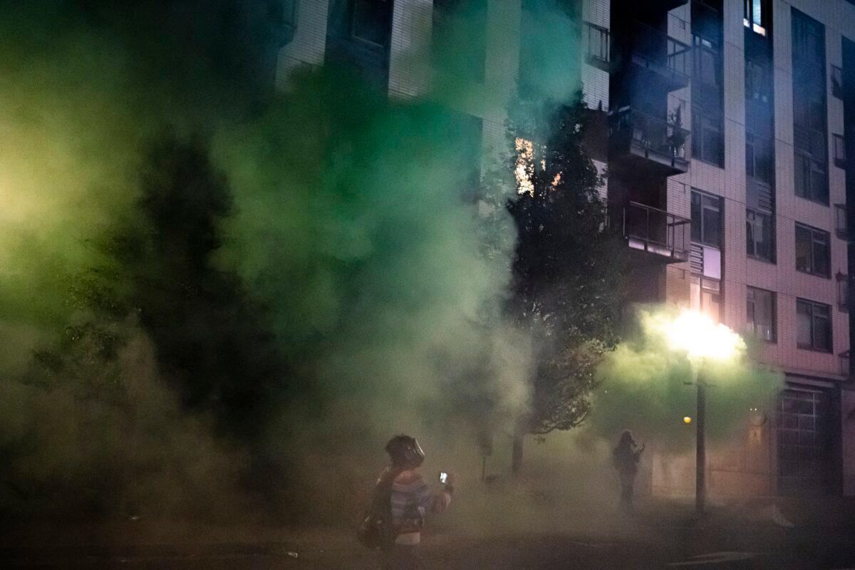 Live streamers walk through clouds of tear gas and smoke following a crowd dispersal in Portland, Ore., late Oct. 6, 2020. (Nathan Howard/Getty Images)