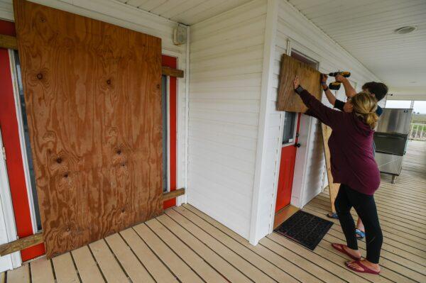 Residents Mamie Russo and her son Cole attach wood to their front door while preparing for Hurricane Delta in Cypremort Point, La., on Oct. 8, 2020, (Brad Kemp/The Advocate via AP)