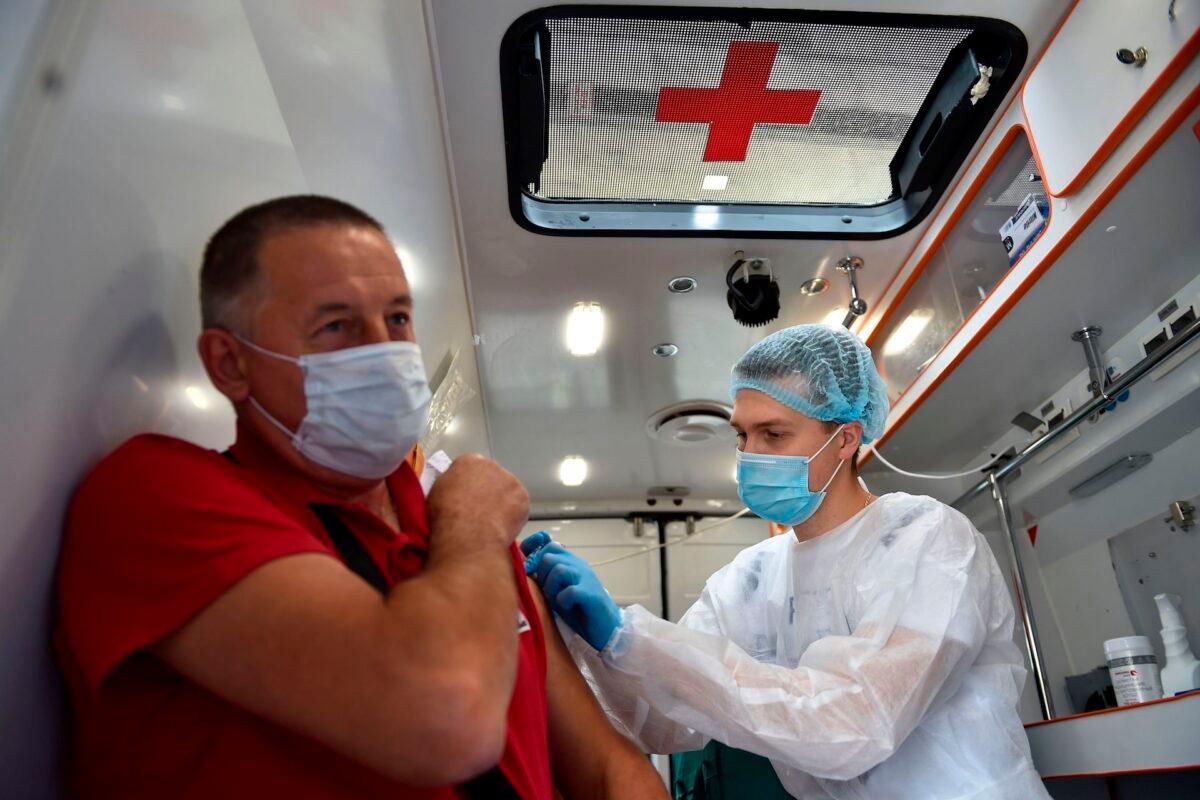 A health care worker vaccinates a man during the seasonal flu vaccination campaign inside a mobile vaccination station in Moscow on Sept. 7, 2020, amid the ongoing coronavirus pandemic. (Natalia Kolesnikova/AFP via Getty Images)