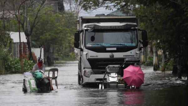 Motorists with an umbrella negotiate a flooded road due to Tyophoon Molave in Pampanga province, northern Philippines, on Oct. 26, 2020. (Aaron Favila/AP Photo)