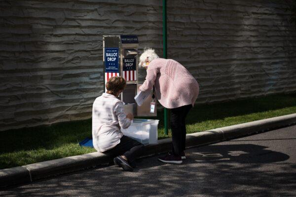Two employees with the Lake County Board of Elections collect absentee ballots from a drop box outside election headquarters in Painesville, Ohio, on Oct. 16, 2020. (Dustin Franz/AFP via Getty Images)
