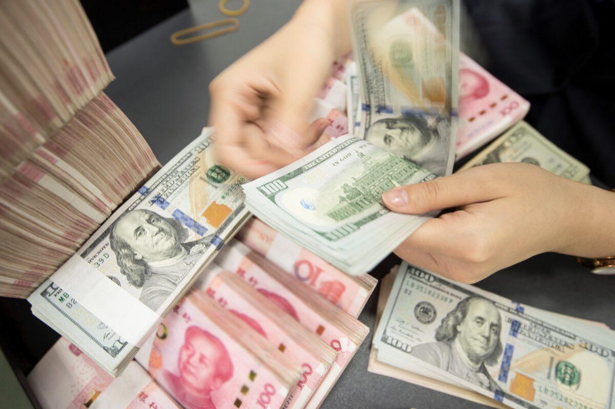 A Chinese bank employee counts 100-yuan notes and U.S. dollar bills at a bank counter in Nantong, Jiangsu Province, China, on Aug. 6, 2019. (STR/AFP via Getty Images)