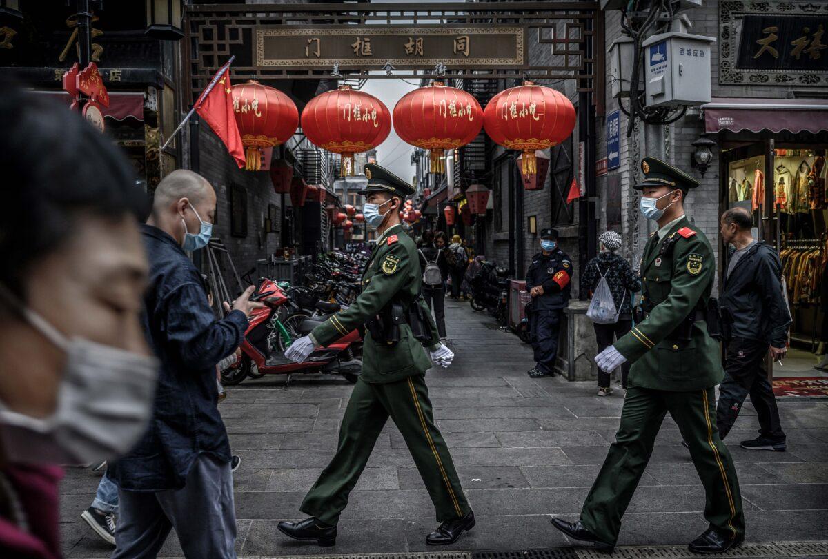 Chinese police patrol as tourists walk in a busy shopping area during the final day of the Golden Week holiday in Beijing on Oct. 8, 2020. (Kevin Frayer/Getty Images)