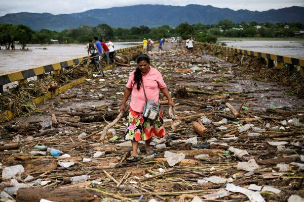 A woman walks among debris on a bridge over the Chamelecon river after the passage of Storm Eta, in Pimienta, Honduras, on Nov. 6, 2020. (Jorge Cabrera/Reuters)