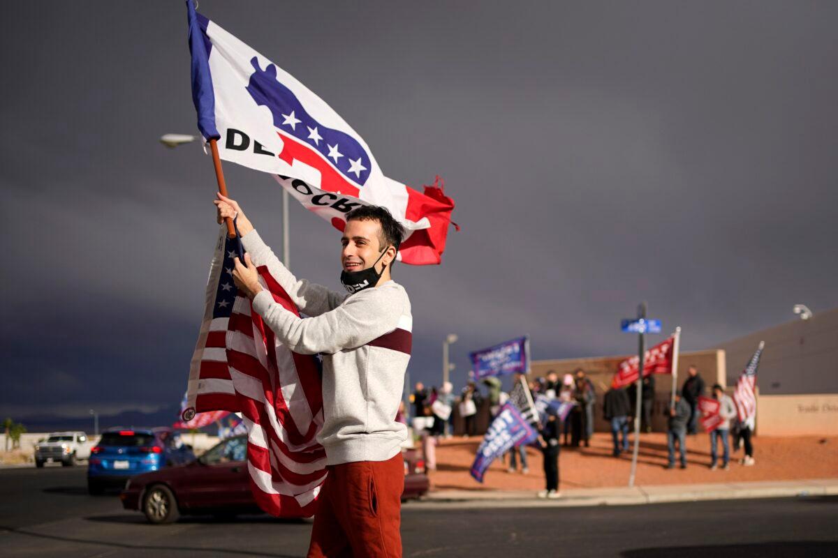 Kevin Abrahami, a supporter of Joe Biden, waves a flag across from supporters of President Trump outside of the Clark County Elections Department, in North Las Vegas, Nev., on Nov. 7, 2020. (John Locher/AP Photo)