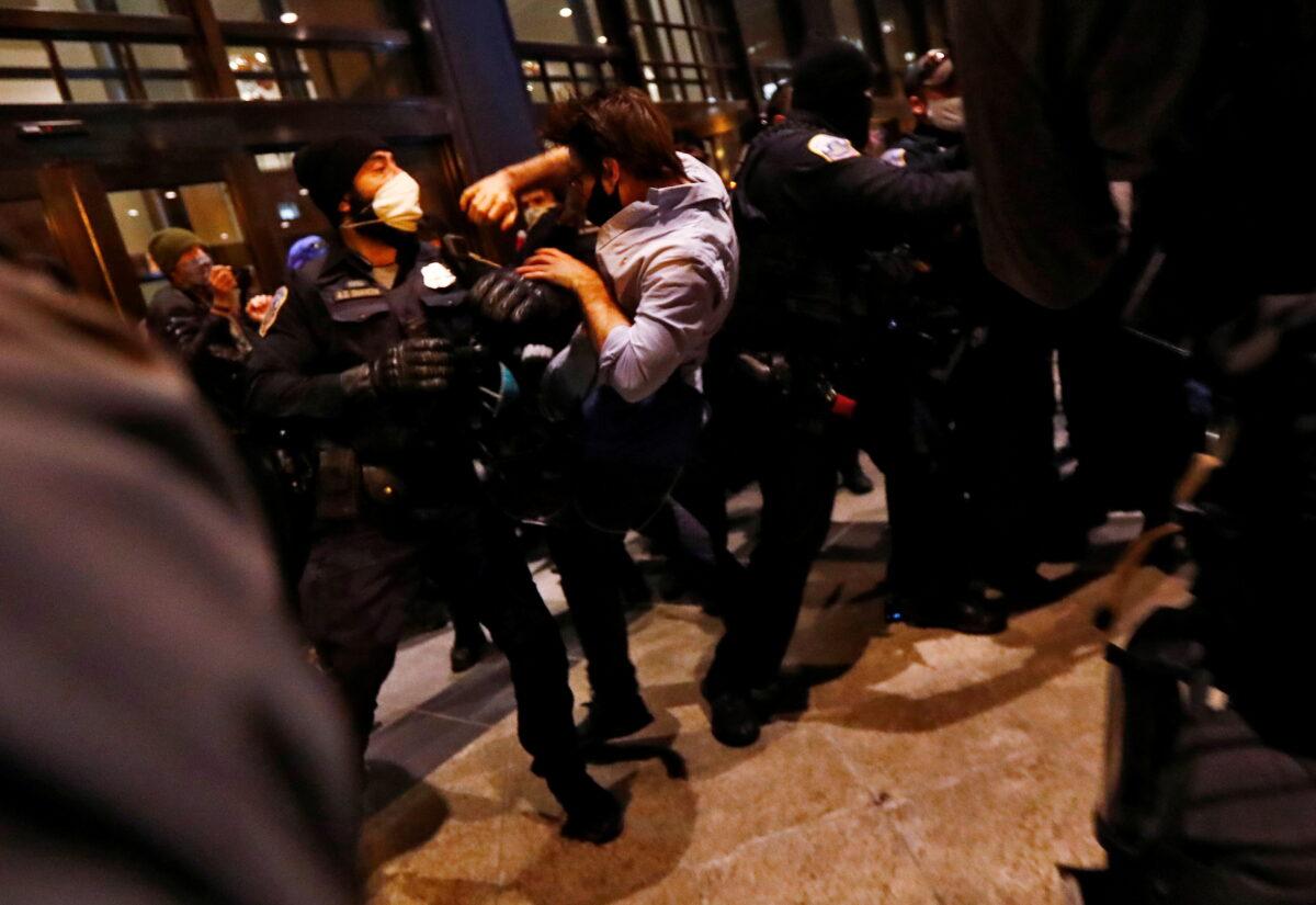 A man is thrown into the air by Washington Metropolitan police officers as Trump supporters and Antifa members clash near the Capital Hilton hotel in Washington on Nov. 14, 2020. (Jim Bourg/Reuters)