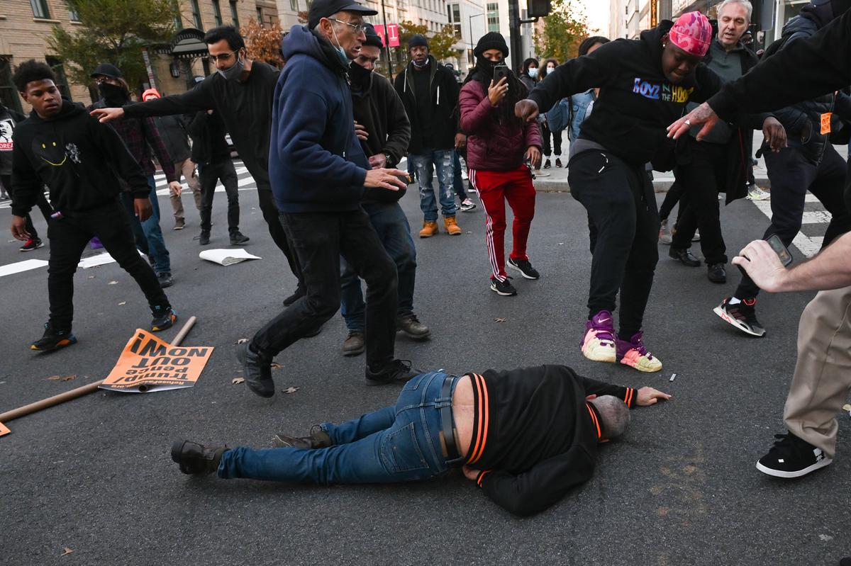 A supporter of President Donald Trump is kicked by an anti-Trump person, after being sucker punched by another, in Washington on Nov. 14, 2020. (Roberto Schmidt/AFP via Getty Images)