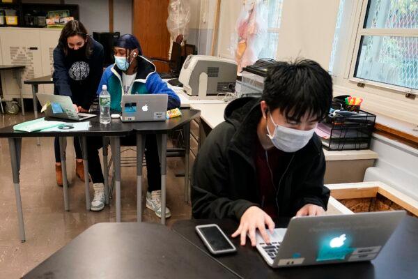 Student Tai Nguyen, right, works on his laptop as instructor Chaya Baras, left, helps student Kenny Scottborough, 19, navigate an online lesson at West Brooklyn Community High School in New York on Oct. 29, 2020. (Kathy Willens/AP Photo)