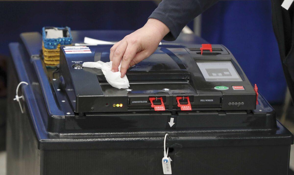A voting machine is cleaned during the Illinois Democratic primary in Chicago, Ill., on March 17, 2020. (Kamil Krzaczynski/AFP via Getty Images)