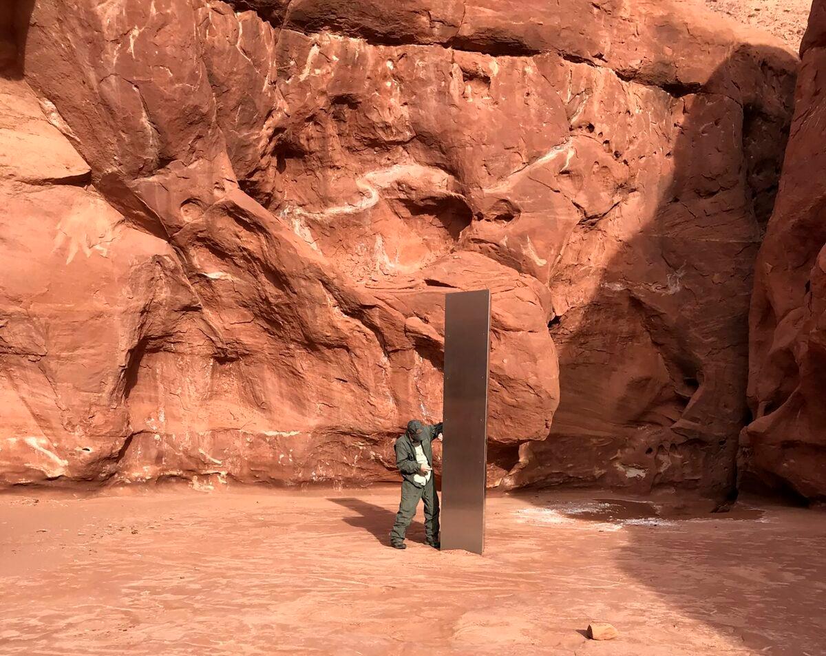 A state worker stands next to a metal monolith in the ground in a remote area of red rock in Utah. (Utah Department of Public Safety via AP)