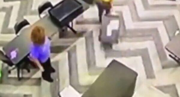 A woman is seen carrying a suitcase or container allegedly filled with ballots without poll challenger supervision on the night of Nov. 3, 2020. (NTD screenshot - State Farm Arena surveillance)