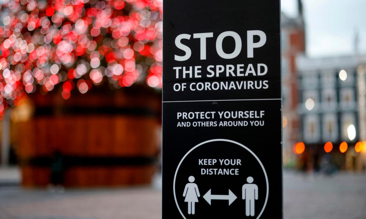 A sign promoting social distancing to combat the spread of the CCP virus is seen beside the Christmas tree in Covent Garden in central London on Nov. 27, 2020. (Tolga Akmen/AFP via Getty Images)