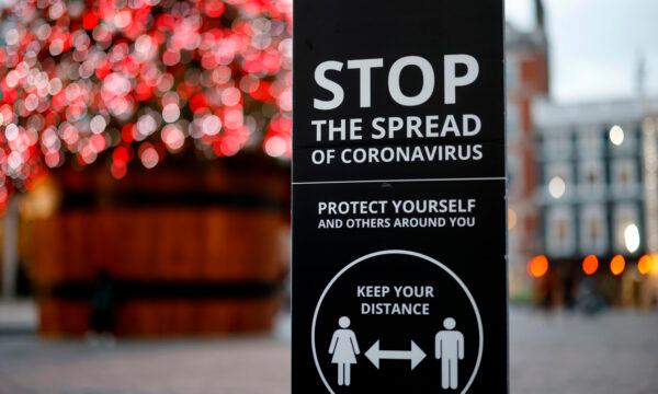 A sign promoting social distancing to combat the spread of the COVID-19 virus is seen beside the Christmas tree in Covent Garden in central London on Nov. 27, 2020. (Tolga Akmen/AFP via Getty Images)