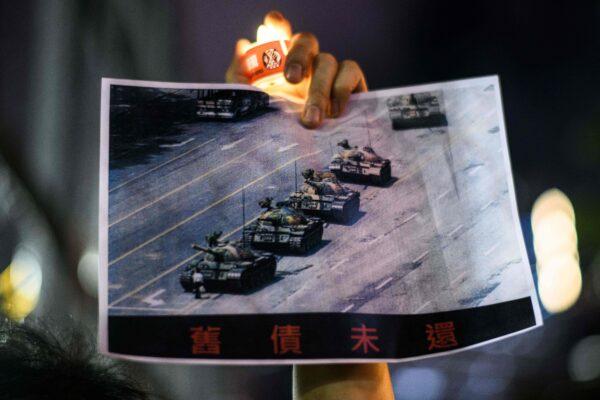 A man holds a poster of the famous 'Tank Man' during the 1989 Tiananmen Square Massacre, during a candlelit remembrance in Victoria Park in Hong Kong on June 4, 2020. (Anthony Wallace/AFP via Getty Images)