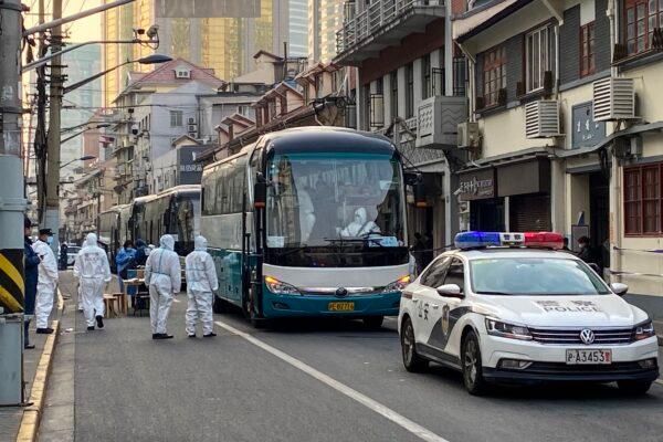 Police and workers arrange buses to evacuate all residents from a neighborhood in Huangpu district to quarantine centers in Shanghai, on Jan. 21, 2021. (STF/AFP via Getty Images)