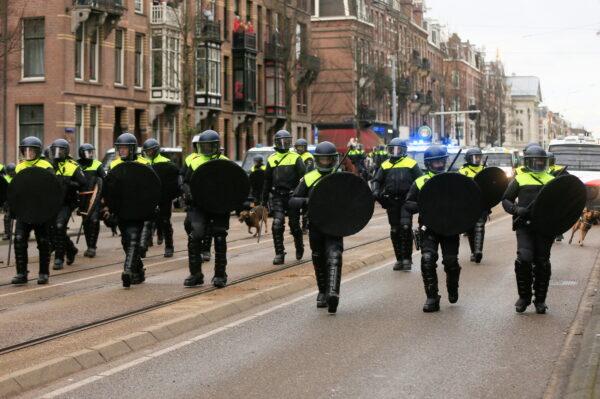 Police officers walk on a street during a protest against COVID-19 restrictions, in Amsterdam, Netherlands, on Jan. 24, 2021. (Eva Plevier/Reuters)