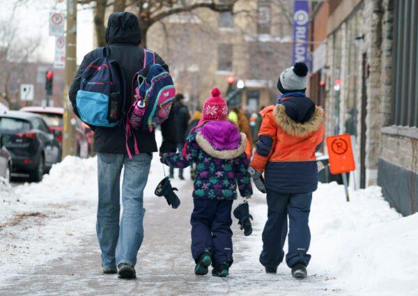 Parents walk their children to school in Montreal on Jan. 11, 2021. (The Canadian Press/Paul Chiasson)
