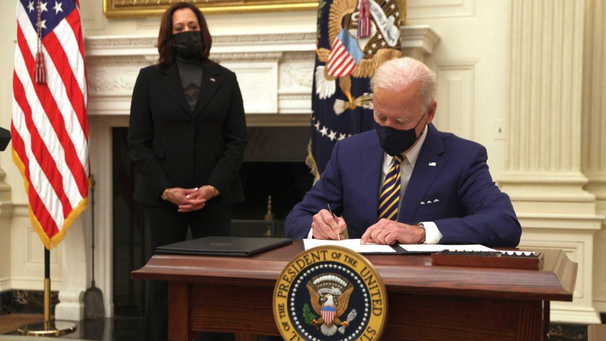 President Joe Biden signs an executive order as Vice President Kamala Harris looks on during an event on economic crisis in the State Dining Room of the White House in Washington Jan. 22, 2021. (Alex Wong/Getty Images)