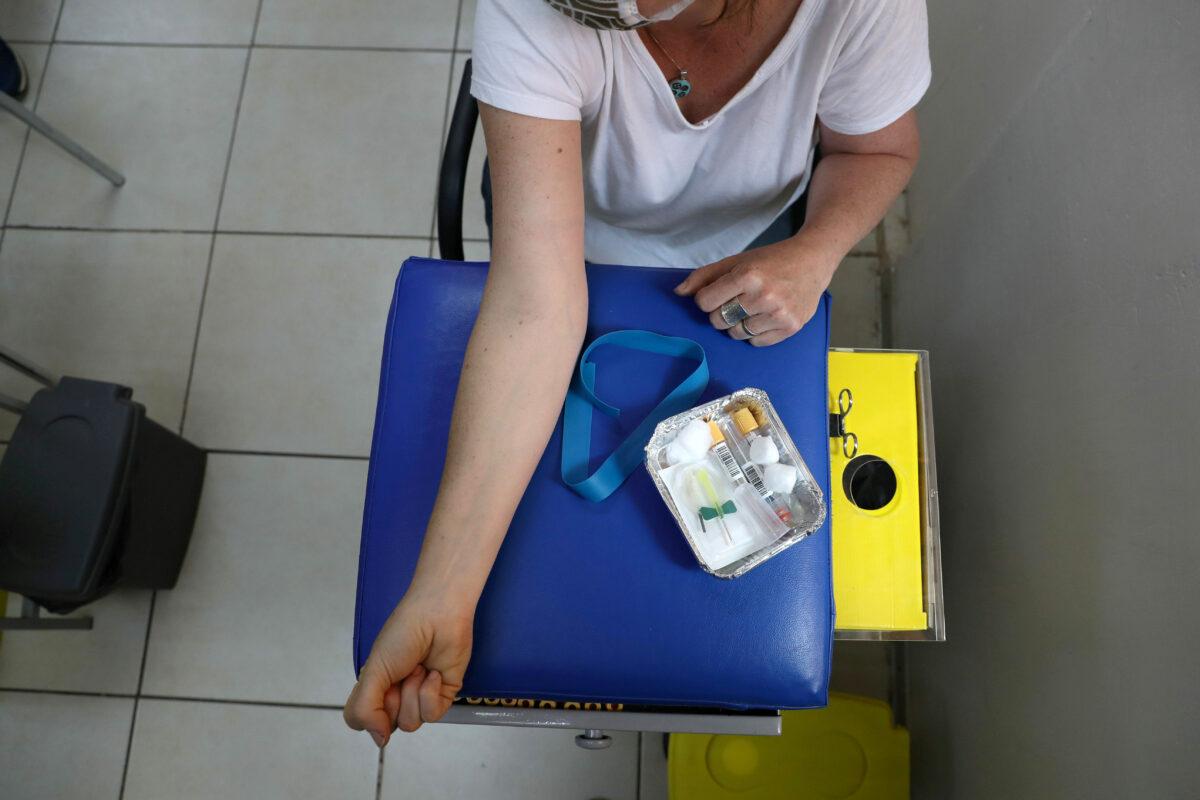 A woman prepares to give a blood sample at a medical facility before receiving a dose of vaccine or placebo of Johnson & Johnson's COVID-19 vaccine clinical trial at Colina area, Santiago, Chile, on Nov. 20, 2020. (Ivan Alvarado/Reuters)