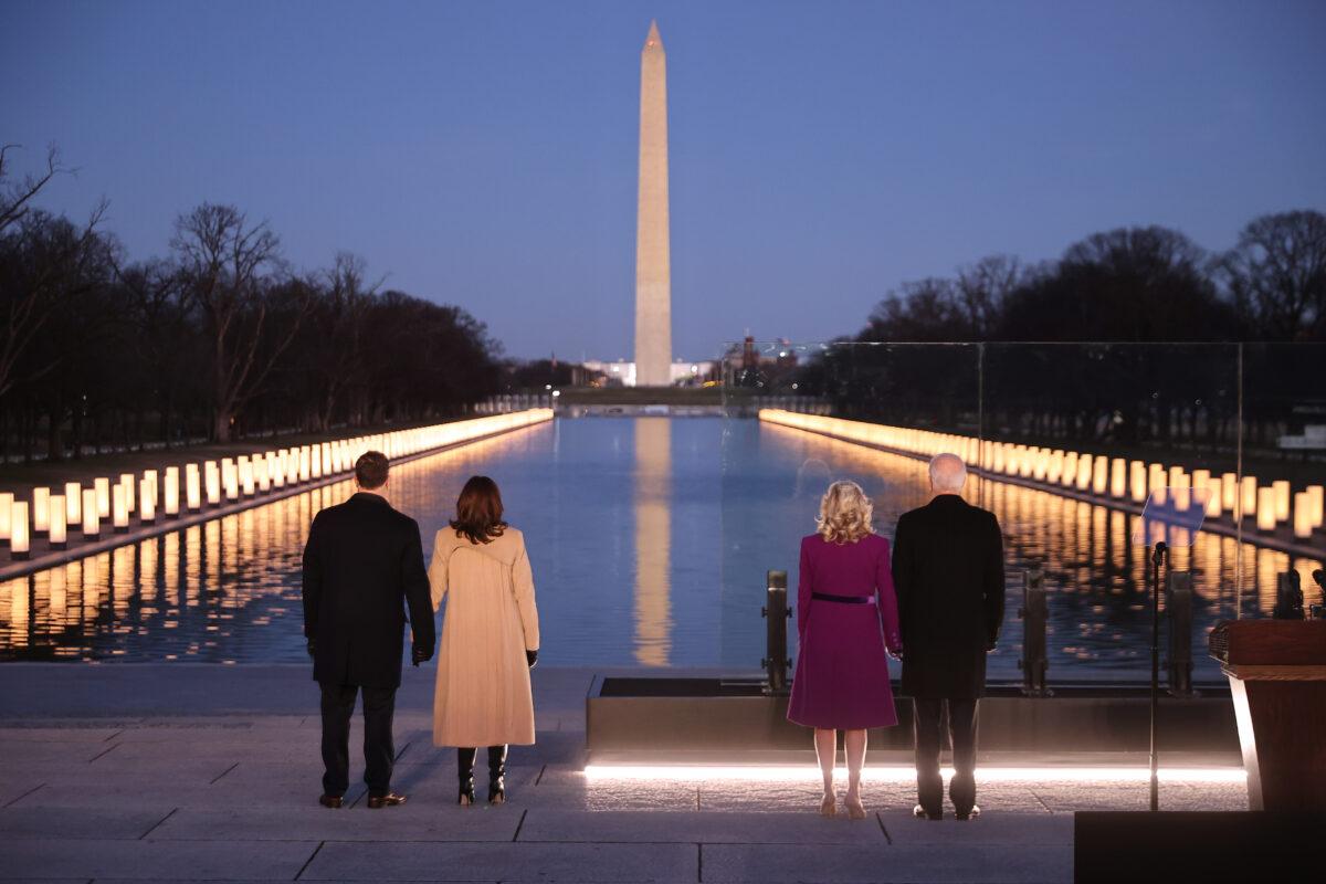 (L-R) Douglas Emhoff, Vice President-elect Kamala Harris, Jill Biden and President-elect Joe Biden look down the National Mall as lamps are lit to honor the nearly 400,000 American victims of the COVID-19 pandemic, at the Lincoln Memorial Reflecting Pool in Washington on Jan. 19, 2021. (Chip Somodevilla/Getty Images)