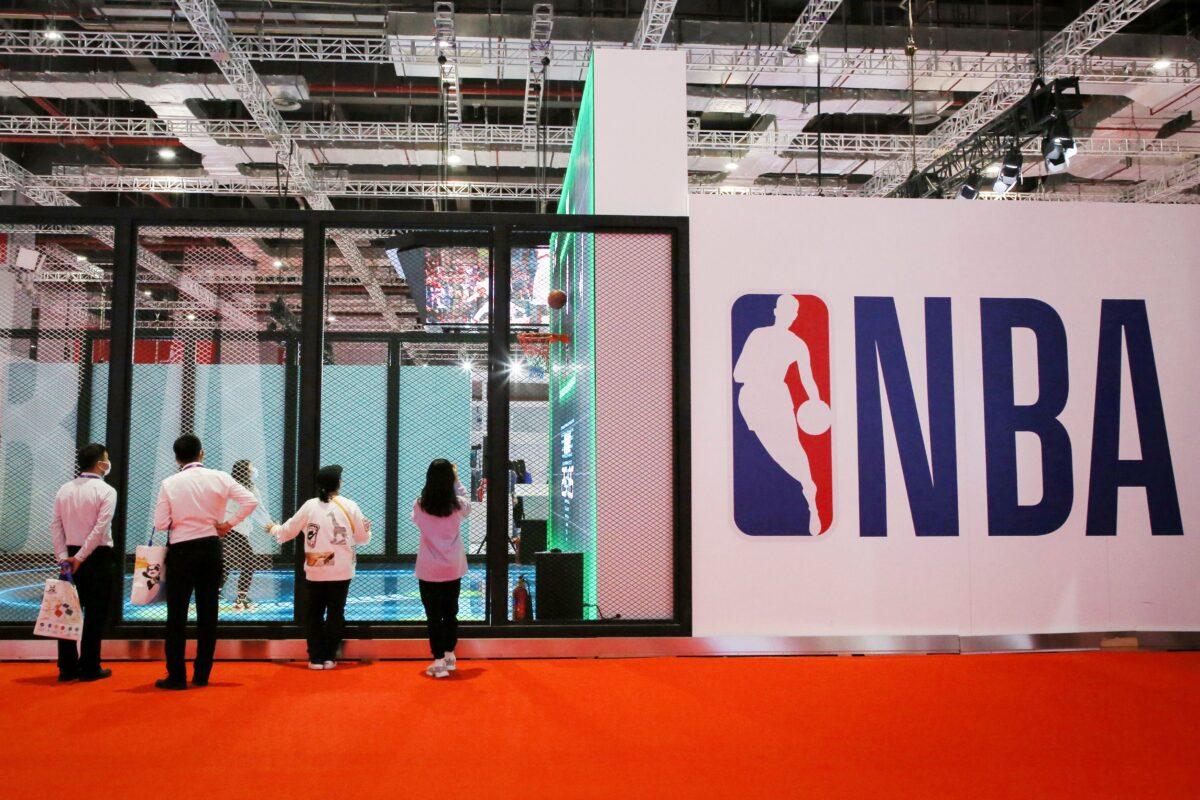 People stand next to an NBA logo at the NBA Exhibition at the 3rd China International Import Expo (CIIE) in Shanghai on Nov. 5, 2020. (STR/AFP via Getty Images)