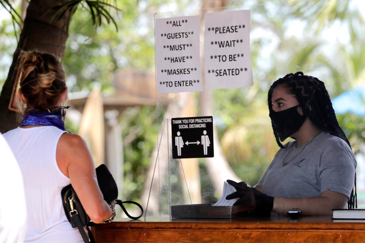 Nailea Rosales works behind a protective shield wearing a protective mask and gloves at the Morada Bay Beach Cafe in Islamorada, in the Florida Keys, on June 1, 2020. (Lynne Sladky/AP, File)