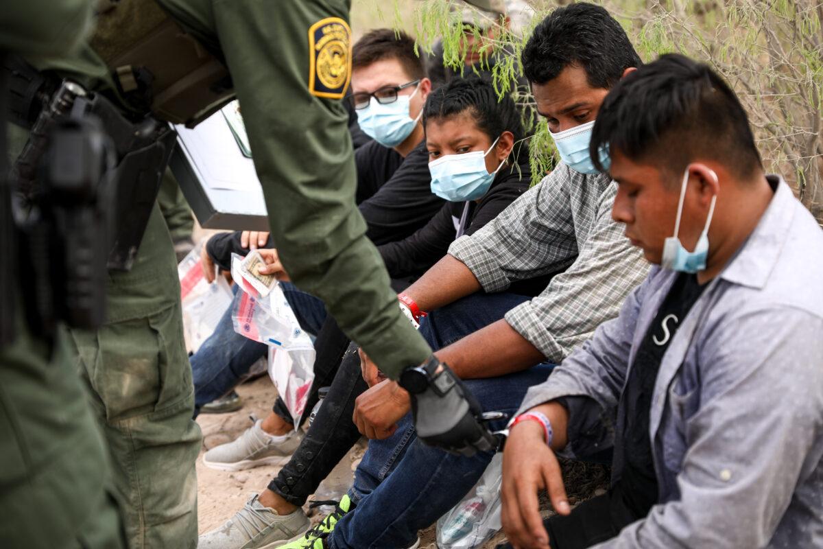 A Border Patrol agent checks an illegal immigrant wears two wristbands that Mexican cartels have been using to control human smuggling into the United States, near Penitas, Texas, on March 15. 2021. (Charlotte Cuthbertson/The Epoch Times)