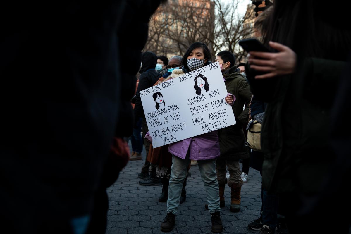 A woman holds a cardboard sign with the names of victims of the Atlanta shootings, at a vigil for victims of Asian hate, in New York on March 19, 2021. (Chung I Ho/The Epoch Times)