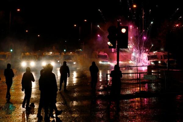 Rioters look on as fireworks go off near the police vehicles on the Springfield Road as protests continue in Belfast, Northern Ireland, on April 8, 2021. (Jason Cairnduff/Reuters)