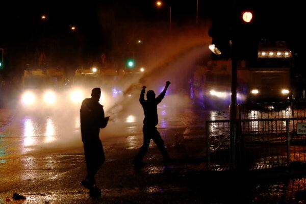 Rioters react as the police uses a water cannon on the Springfield Road as protests continue in Belfast, Northern Ireland, on April 8, 2021. (Jason Cairnduff/Reuters)