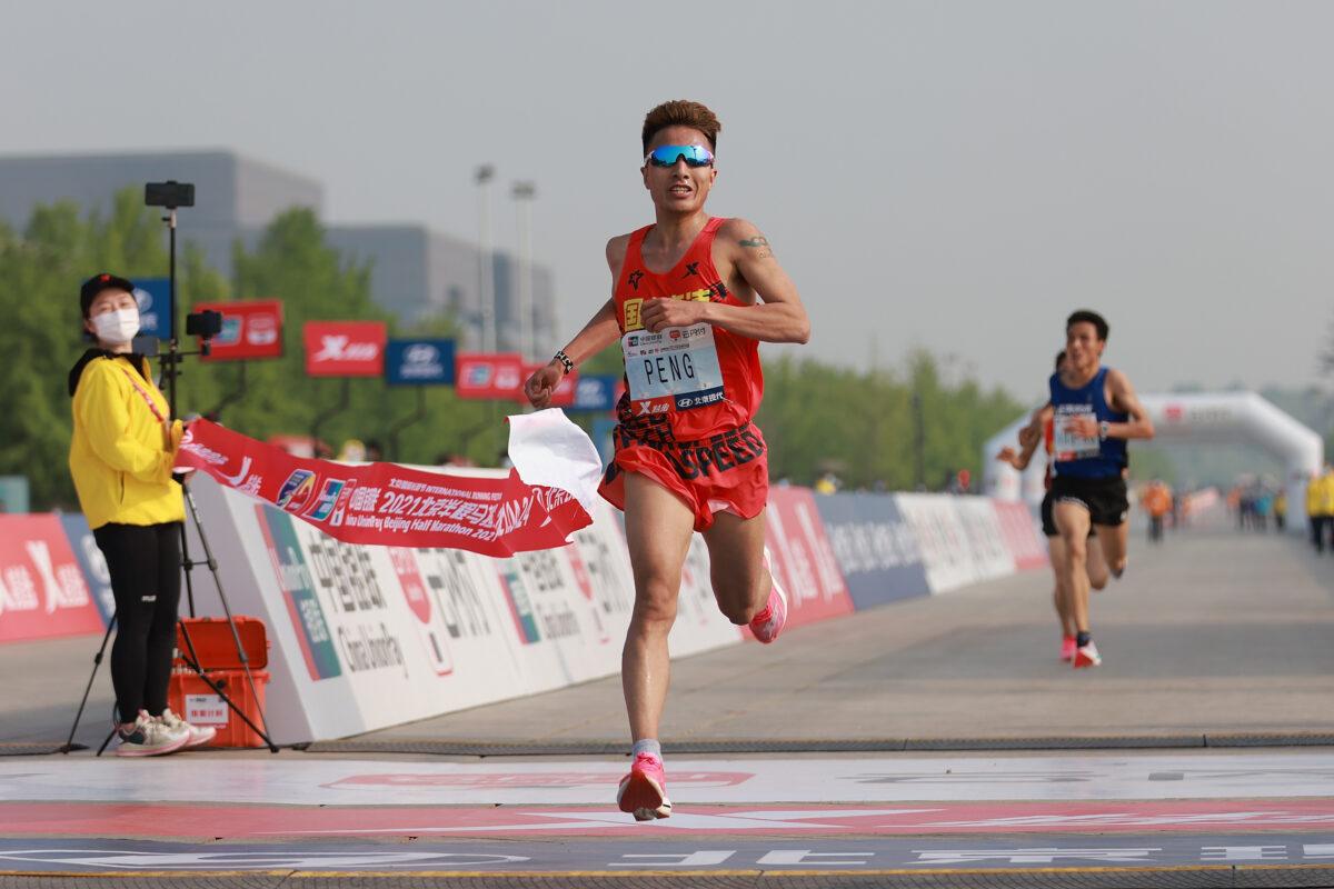 Peng Jianhua celebrates after crossing the finish line to win first place in the men's category during the 2021 Beijing Half Marathon at Tiananmen Square in Beijing, on April 24, 2021. (Lintao Zhang/Getty Images)