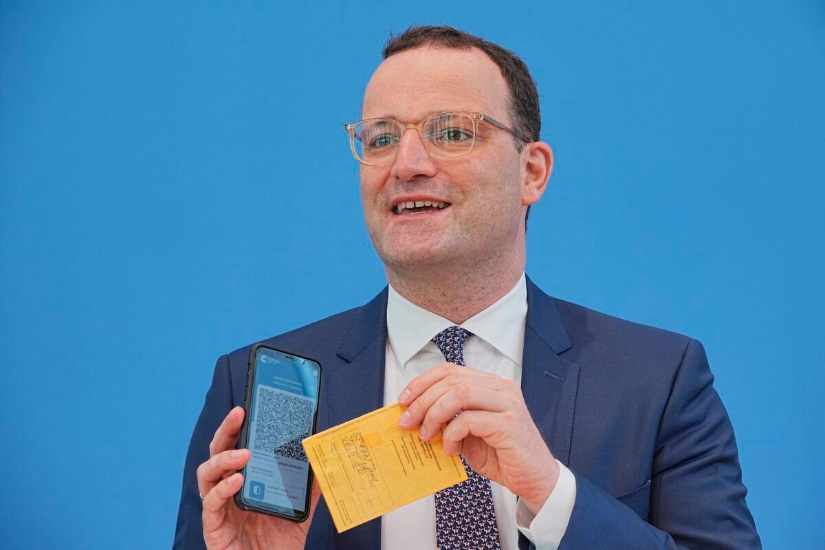 Jens Spahn (CDU), Federal Minister of Health, shows the Corona Warn app with a sample digital vaccination certificate as well as his own old vaccination certificate at the regular press conference on the Corona situation in Berlin, Germany, on June 10, 2021. (Michael Kappeler/dpa via AP)