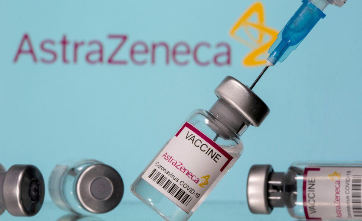 Vials labelled "AstraZeneca COVID-19 Coronavirus Vaccine" and a syringe are seen in front of a displayed AstraZeneca logo, in this illustration photo taken on March 14, 2021. (Dado Ruvic/Illustration/Reuters)