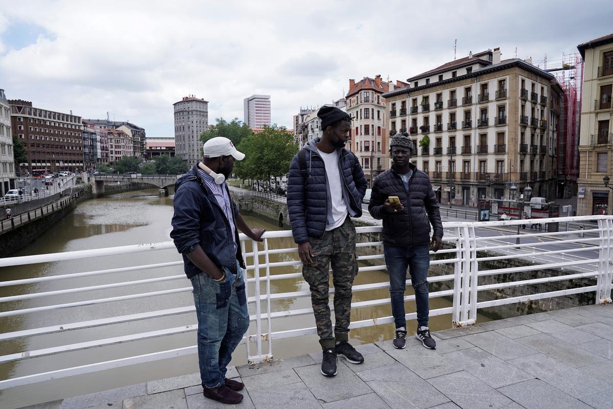 Mohamed Fadal Diouf, 26, from Senegal, stands with friends on a pedestrian bridge over the river Nervion in Bilbao. (Reuters/Vincent West)
