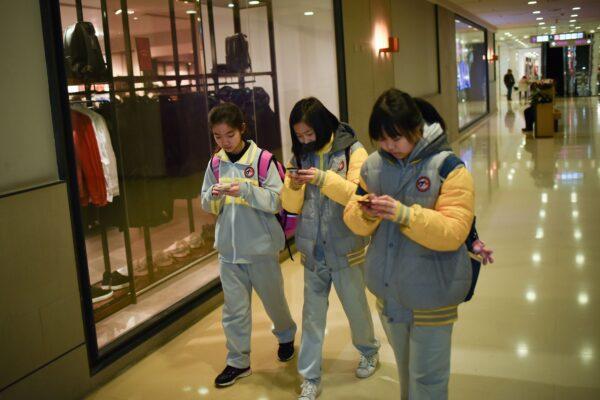 Students use their mobile phones while walking in a mall in Beijing, China on Jan. 26, 2018. (Wang Zhao/AFP via Getty Images)